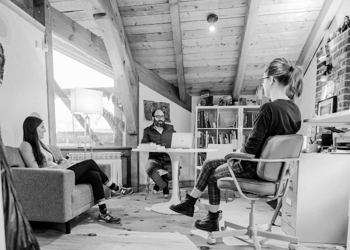 A black and white photo of Karen, Andrew, and Nicky sitting casually in a triangle in Andrew's smaller office, talking.