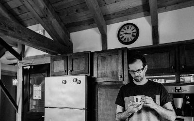 A black and white photo of Dan sipping coffee on a saucer in the Manoverboard kitchen.